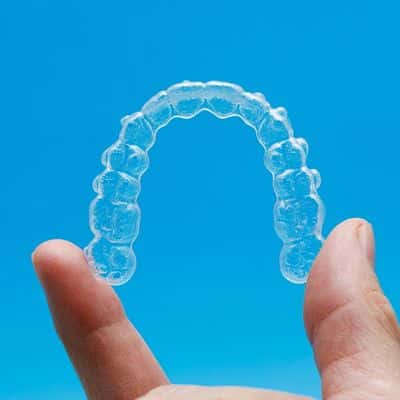 What is invisalign? 4 Invisalign aligners held between two fingers