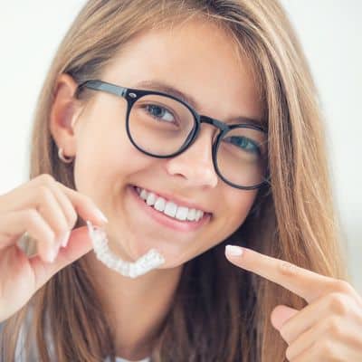 Invisalign care tips 8 Young woman with glasses pointing to invisalign aligners
