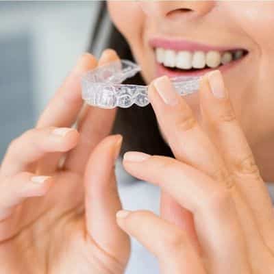 Caring for invisalign 4 Woman holding invisalign aligners near mouth