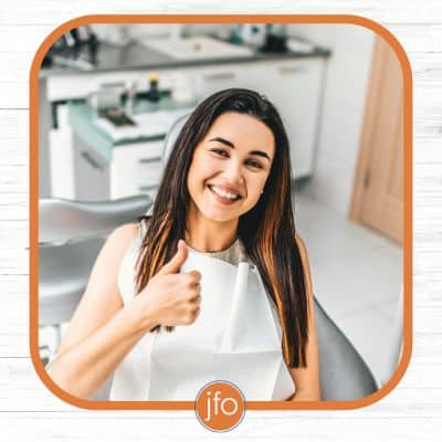Ask us about lightforce braces 6 Female patient in dental chair holding up a thumbs up