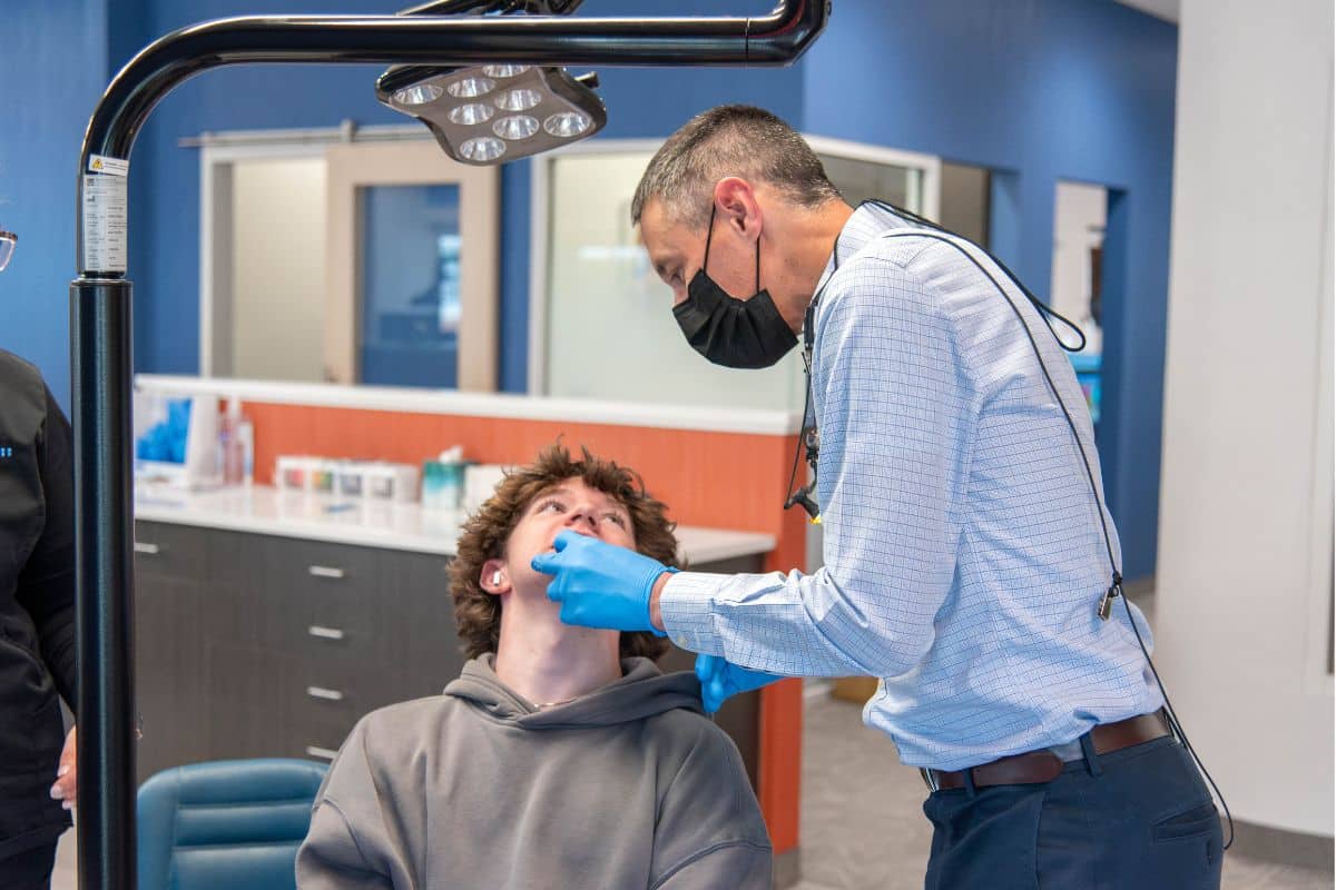 A man in a mask and gloves examining a patient's mouth