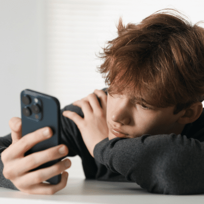 The truth about looksmaxxing 2 Young person looking at smartphone thoughtfully, representing what is looksmaxxing